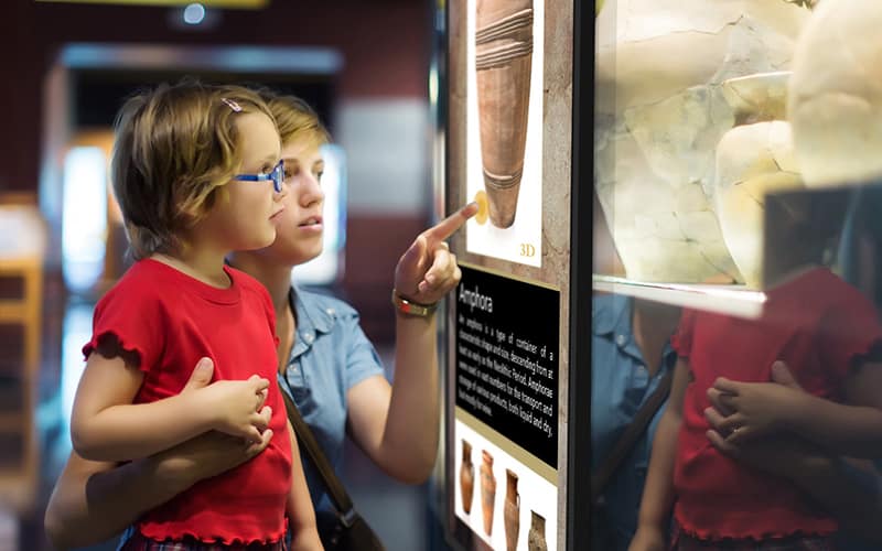 Woman and child using NEC touchscreen digital signage at a museum