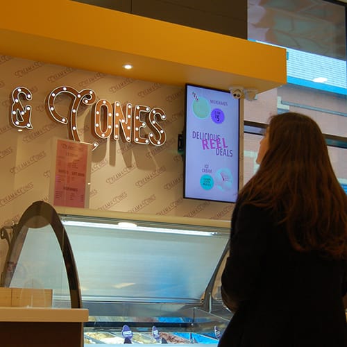 Woman looking at digital signage at an ice cream counter in a cinema in Rochdale, Manchester