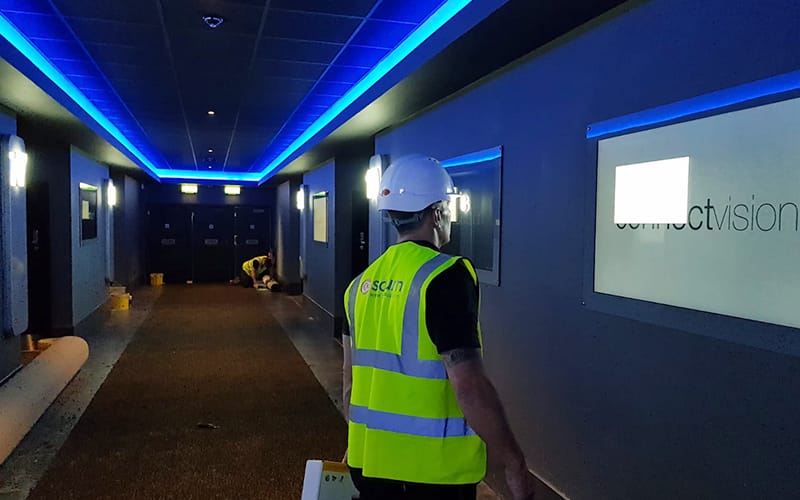Engineer in PPE carrying digital signage equipment