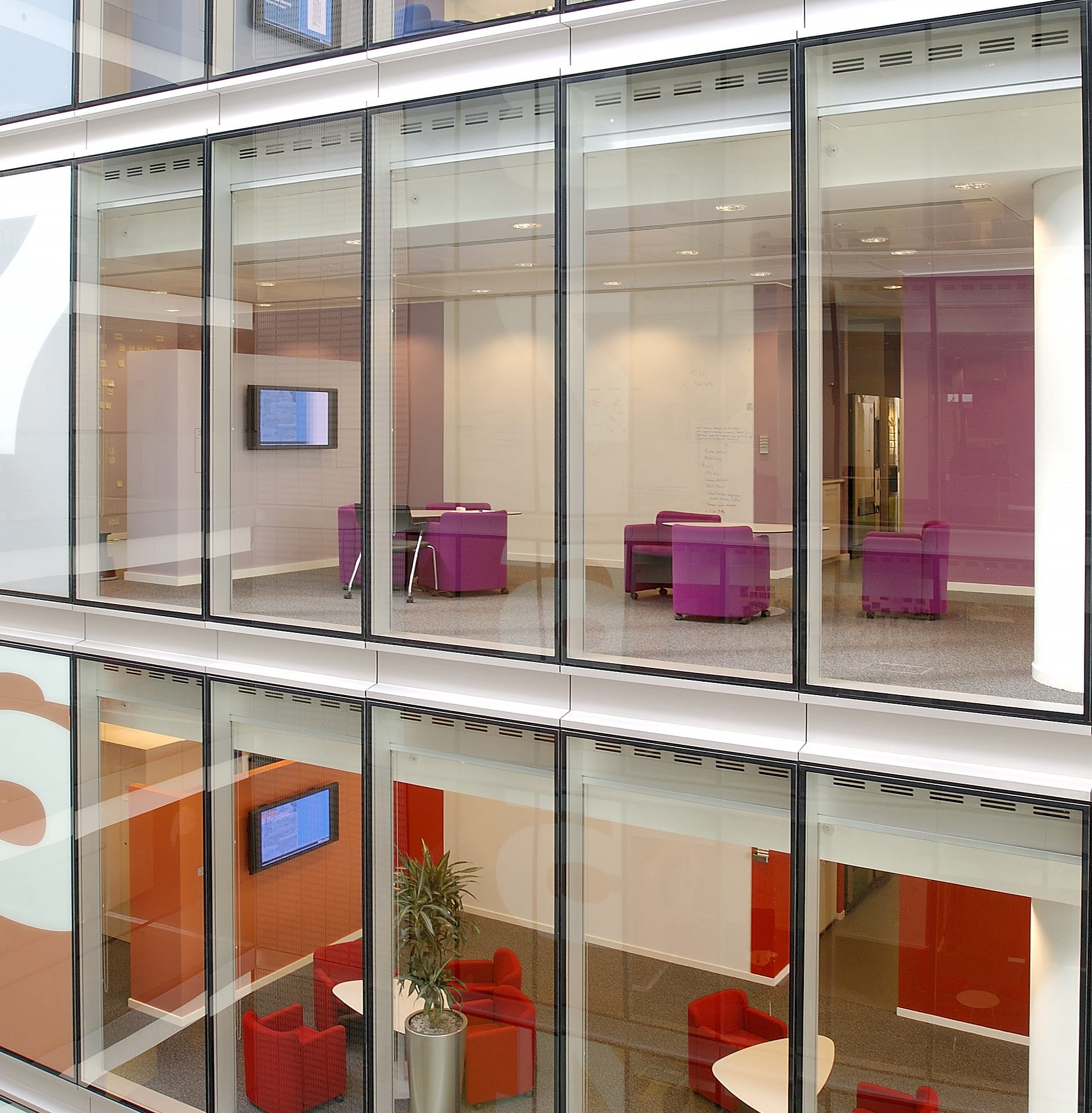 Corporate Digital Signage | An image showing digital signage on different floors within an office space through floor-to-ceiling windows