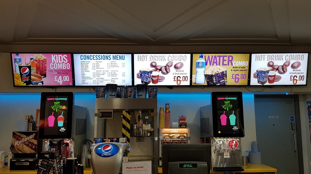 Menu board digital signage above a serving counter in a cinema