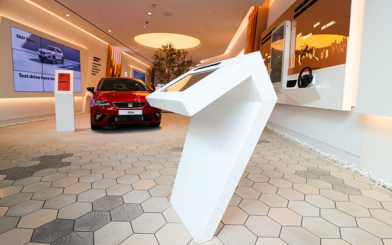 Bespoke white freestanding futuristic digital signage enclosure in a SEAT car showroom