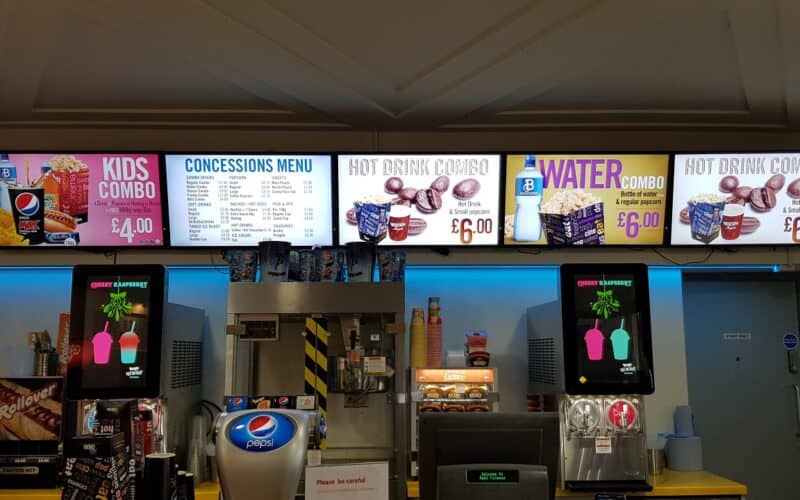 Menu board digital signage above a serving counter in a cinema
