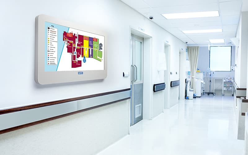 Wall-mounted wayfinding digital signage in a hospital corrridor