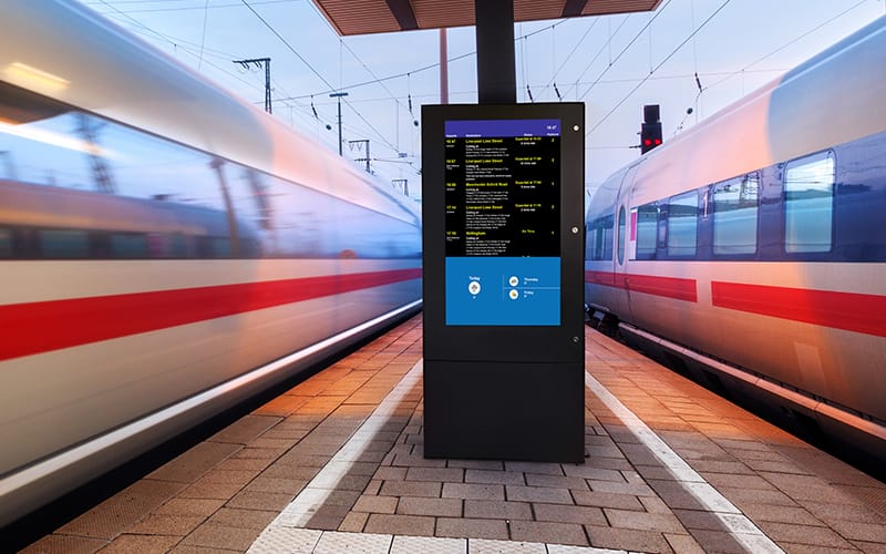Digital signage display showing timetable information to passengers at a UK train station