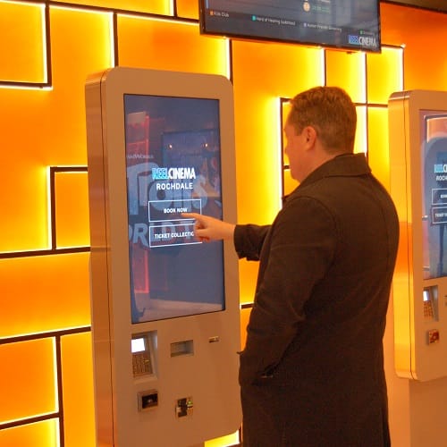 Man using freestanding, interactive digital signage kiosk screen at a Cinema