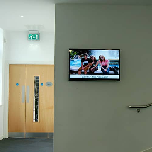 Digital signage screen at Winstanley College in the corridor showing student field trips
