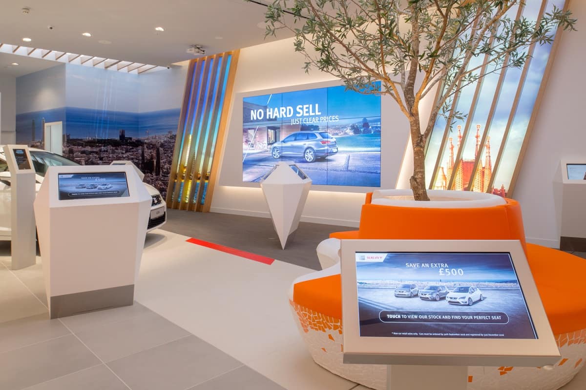 Digital signage video wall and two interactive kiosk screens at car showroom