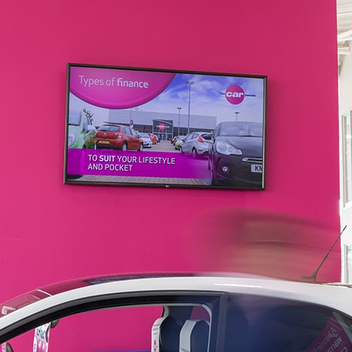 Digital signage screen showing finance information in a car showroom