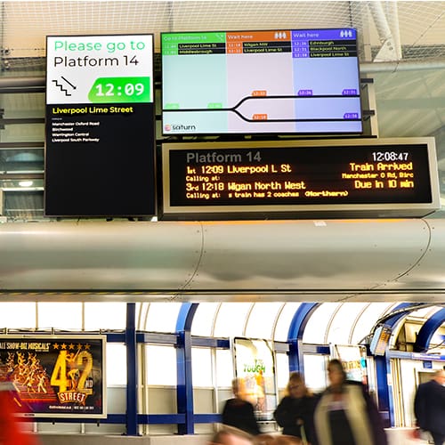 Passenger information displayed on digital signage screens at a railway station in Manchester