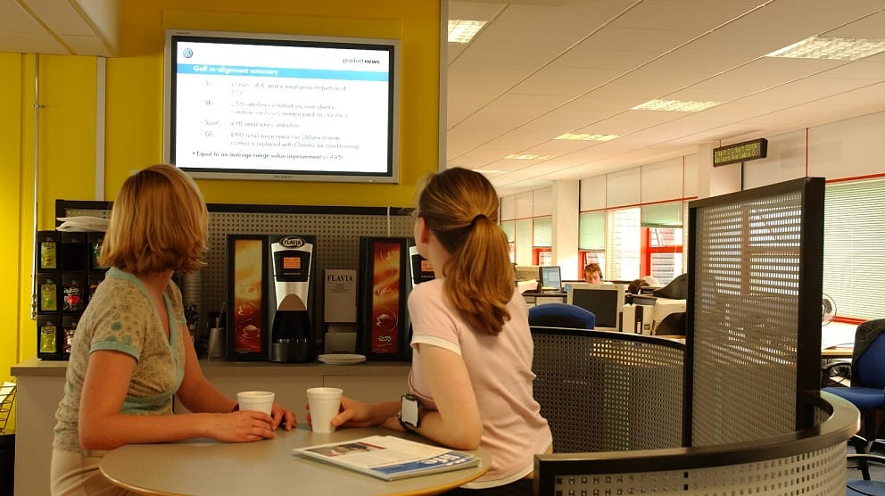 Internal communications messages appearing on digital signage in the breakout area of an office