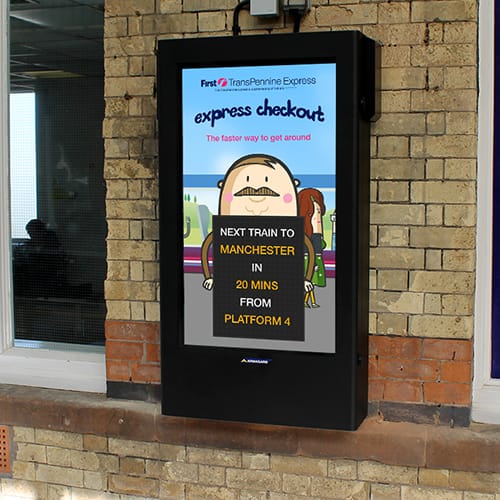 Wall-mounted digital signage on a railway platform showing train proximity