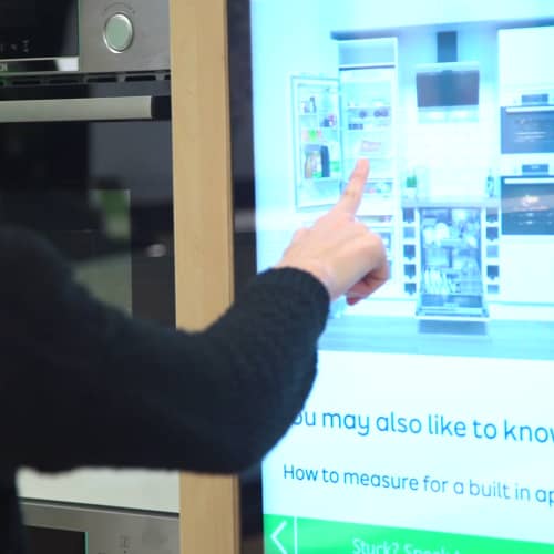 Customer using touch screen digital signage in an electrical retail store to learn about built-in applicances